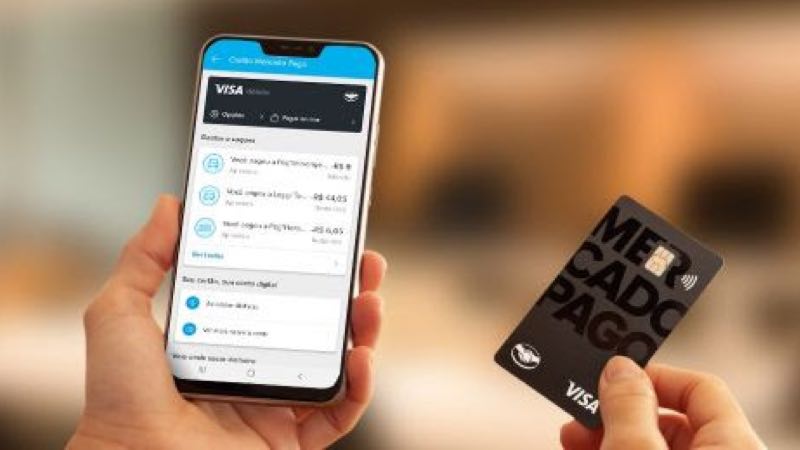 Pessoa com celular e cartão Mercado Pago Visa