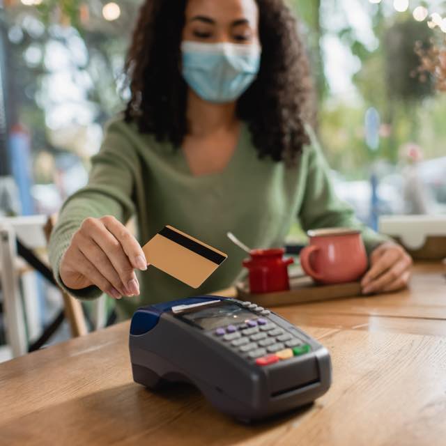 Mulher passando cartão bancário na máquina de cartão