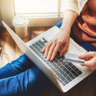 Pessoa com notebook e cartão na mão.