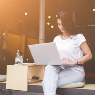 Mulher sentada com notebook no colo.