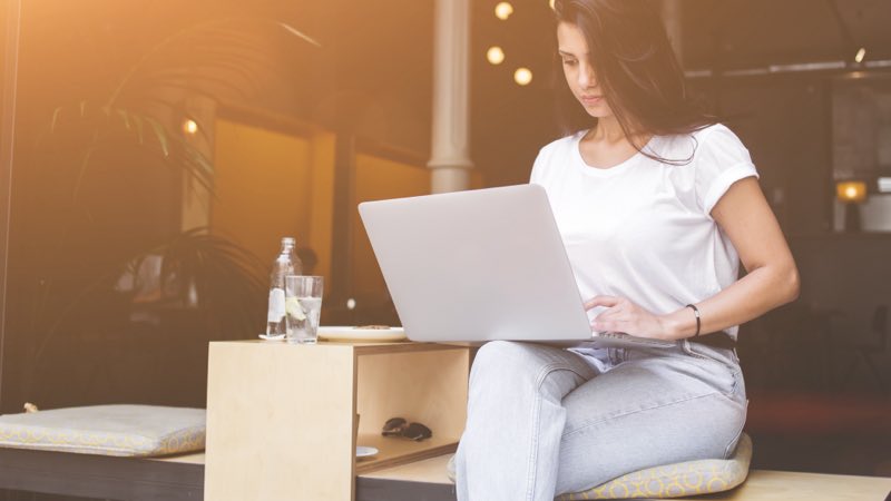 Mulher sentada com notebook no colo.