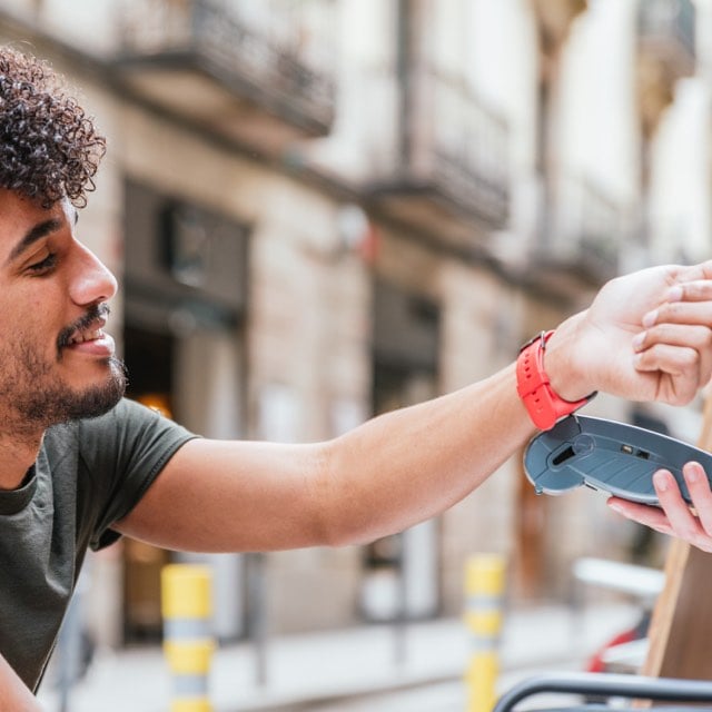 Imagem exibe homem efetuando pagamento por aproximação com smart watch