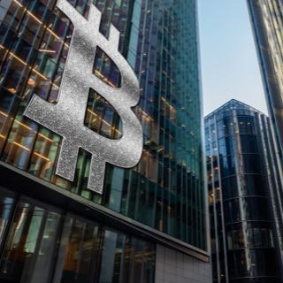 Fachada de um prédio corporativo com o símbolo ₿, referente a Bitcoin