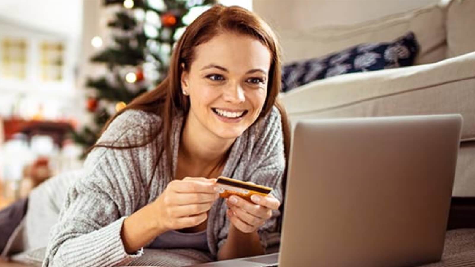 Imagem de uma mulher realizando compras online com um cartão de crédito em mãos