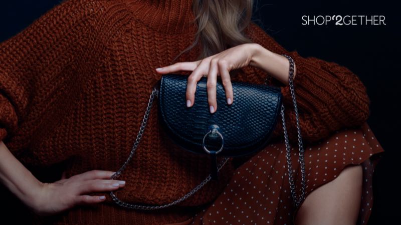 Fotografia de uma modelo bem vestida com uma bolsa na mão com o logo da SHOP'2GETHER ao lado.