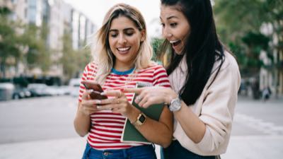 Duas mulheres sorrindo e olhando o smartphone